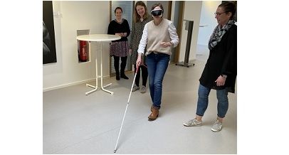 Selbsterfahrung bei der Fortbildung bauliche Barrierefreiheit in Detmold im Mai 2023: eine Teilnehmerin übt mit einem Blindenlangstock und Simulationsbrille.