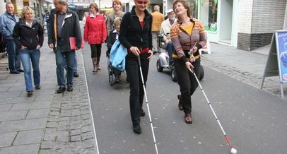 Zwei Frauen mit Langstock bei einem Stadtrundgang mit weiteren Personen