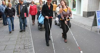 Zwei Frauen mit Langstock bei einem Stadtrundgang mit weiteren Personen