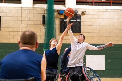 4 Personen im Rollstuhl spielen Basketball in einer Sporthalle
