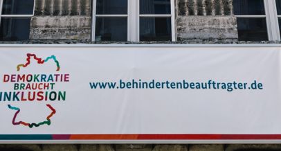 Plakat zeigt Logo "Demokratie braucht Inklusion" und die Webseite www.behindertenbeauftragter.de