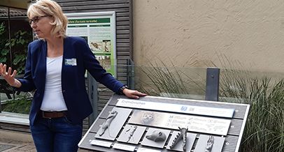 Eine Frau an der tastbaren Infotafel am Tierpark Bochum