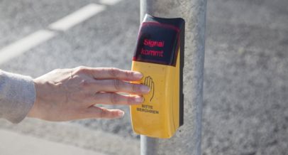 gelber Anforderungstaster am Ampelmast mit der Aufschrift bitte berühren und leuchtender Text Signal kommt